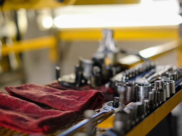 A workbench with red cloths, various wrenches, and sockets neatly arranged, with tools and machinery parts in the background—ideal for air conditioning services or AC repairs.