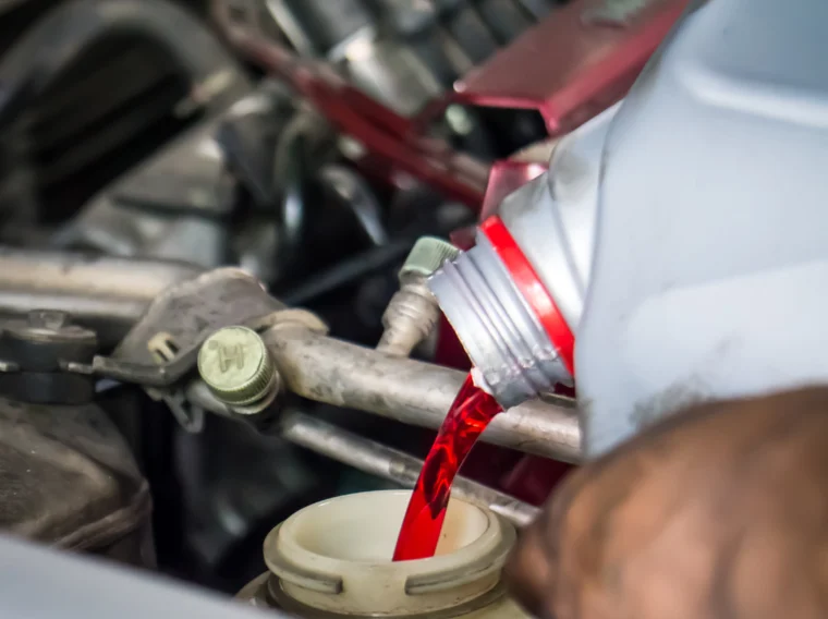 Hand pouring transmission fluid into a reservoir.
