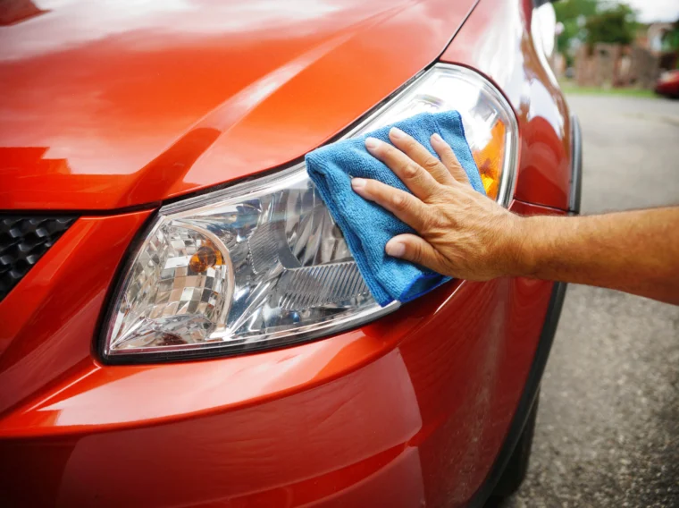 A hand cleaning a car's headlights.